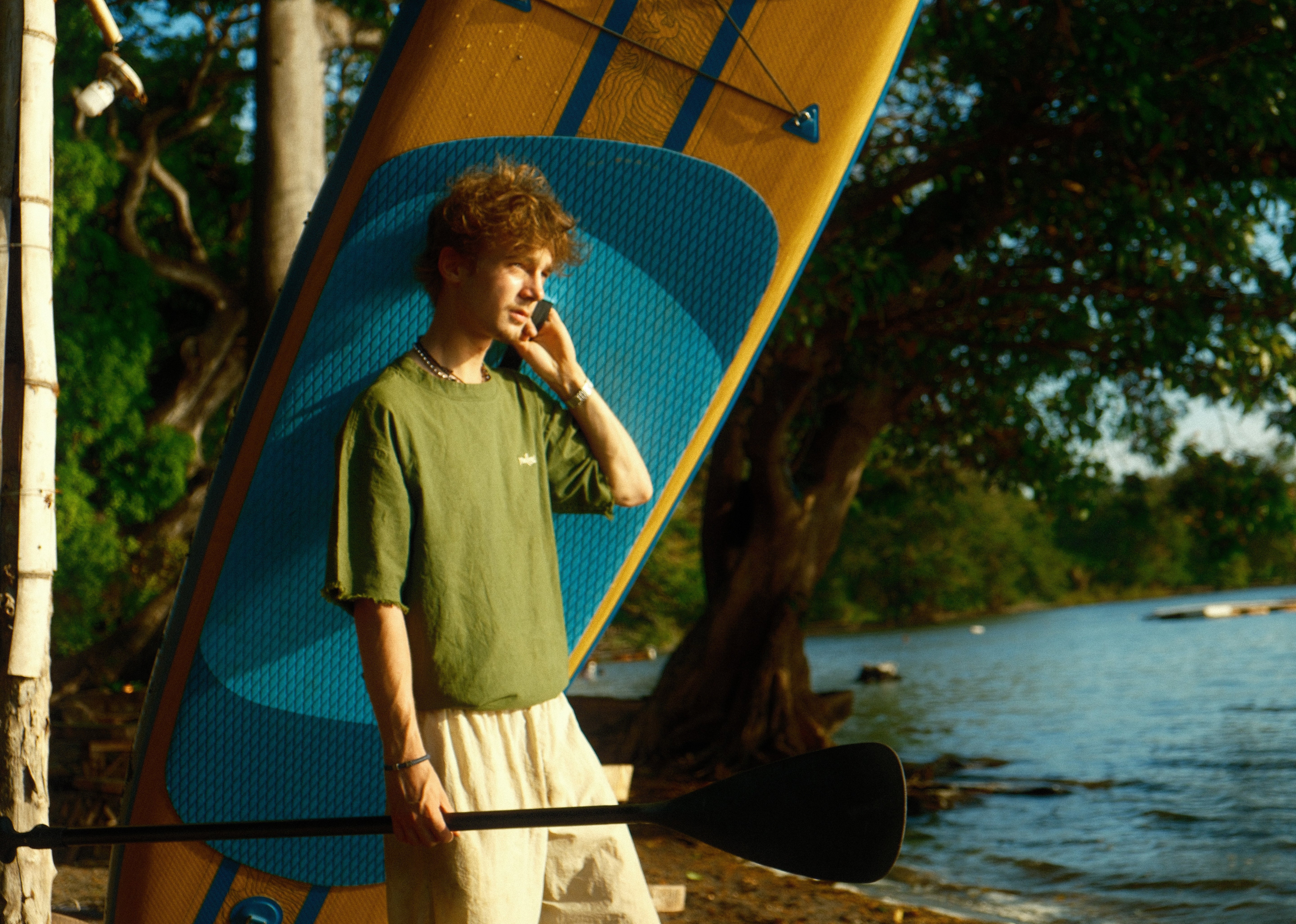 Person holding a paddle and a surfboard with a scenic background