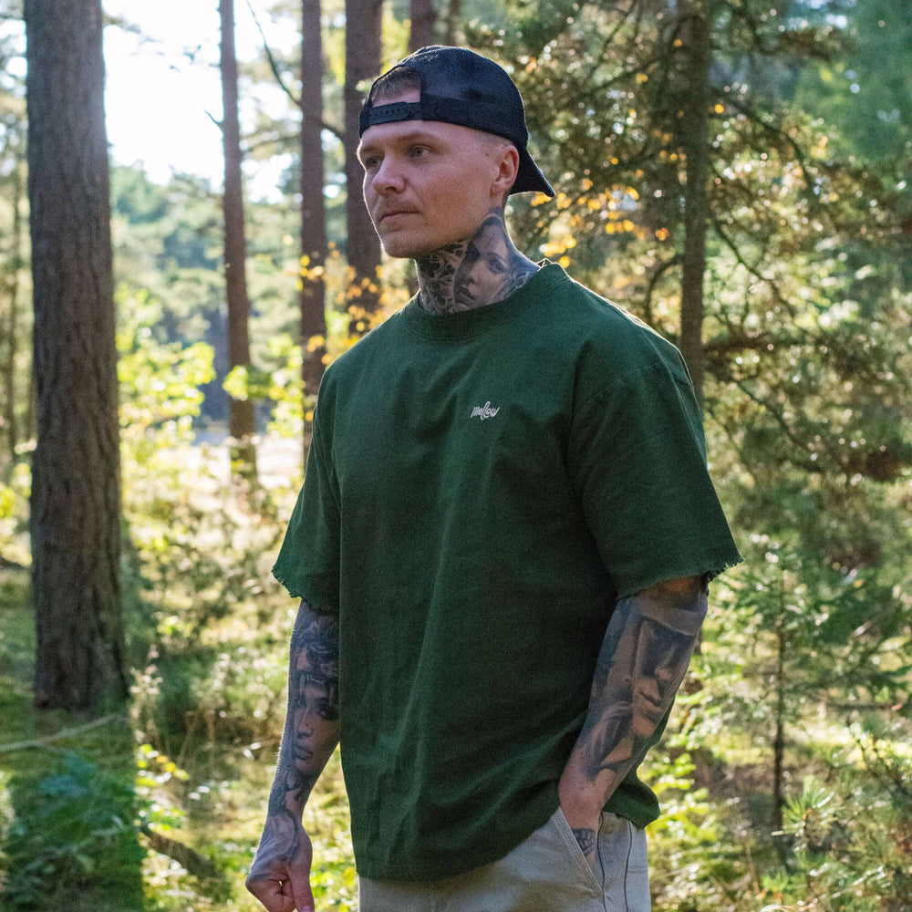 Man wearing a green hemp t-shirt and beige pants standing in a forest