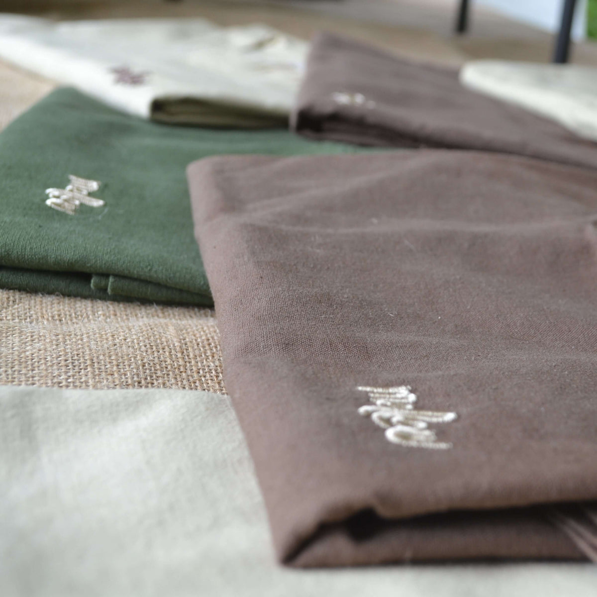 Folded brown hemp t-shirt with a brand logo on a wooden surface