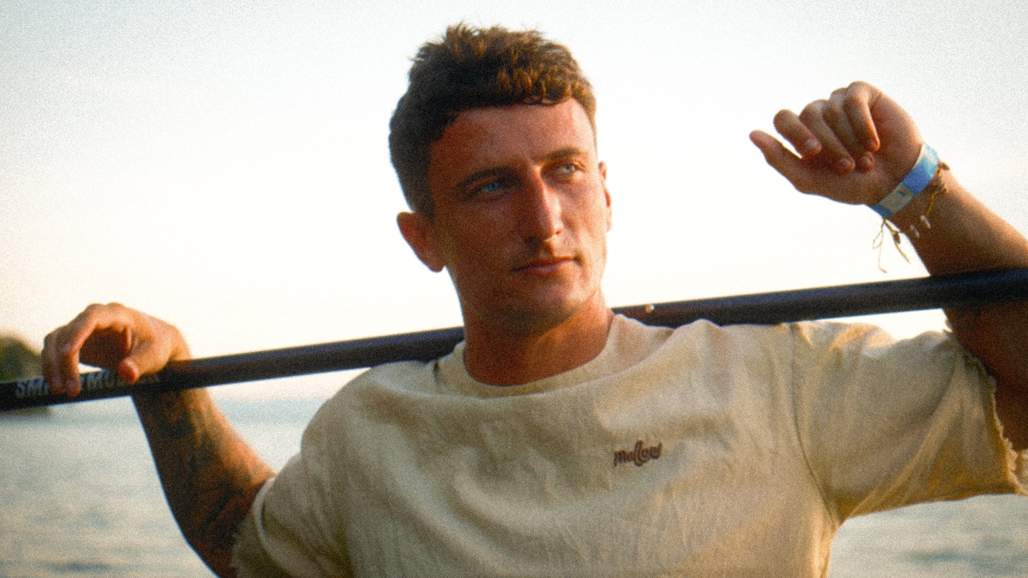 Man holding a fishing rod with a blurred natural background wearing Hemp